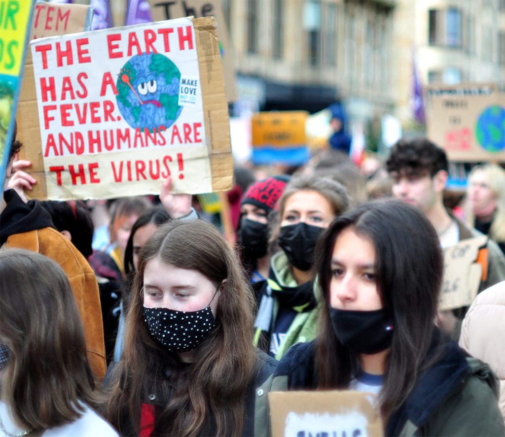 Climate protest with placard "The earth has a fever and humans are the virus"