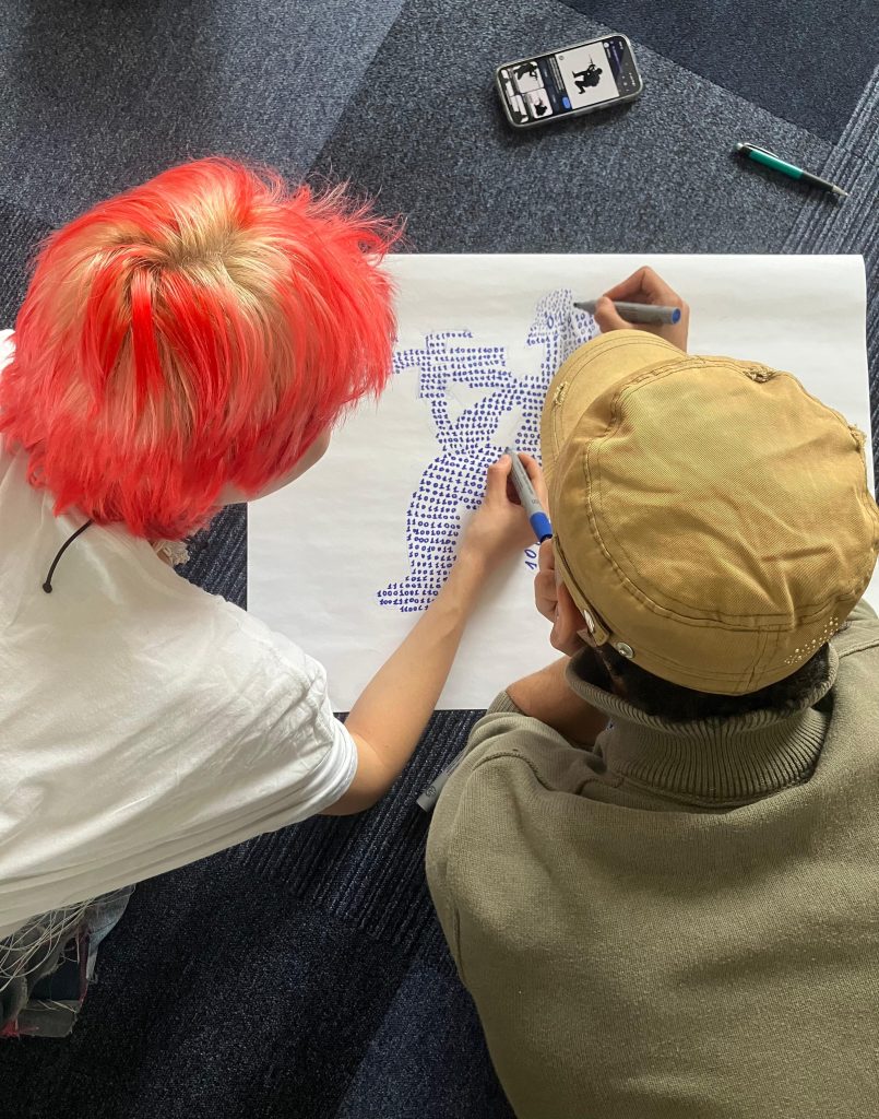 Two participants making a poster of a soldier in binary code for one of the activities, taken by Kerry
