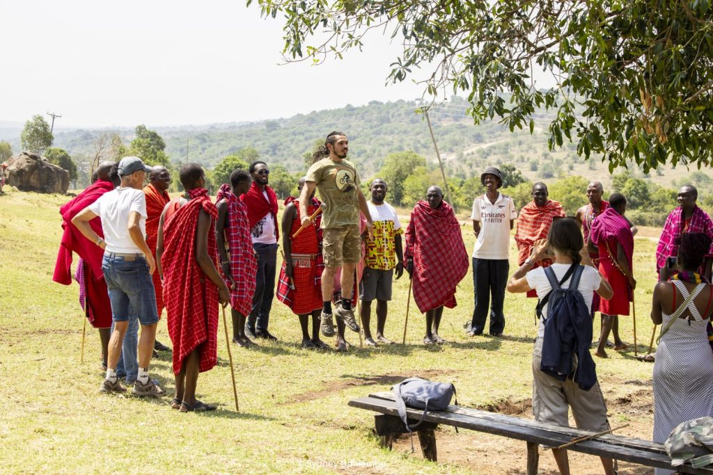 A volunteer jumping and other people in a circle looking at him smiling