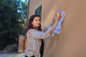 Fatma hanging a poster and smiling.