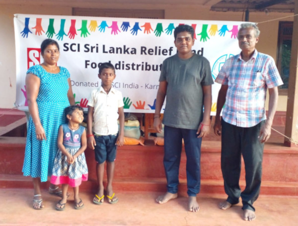 A family and our volunteer in front of the banner