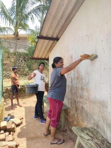 two women paining the wall of a school in sri lanka