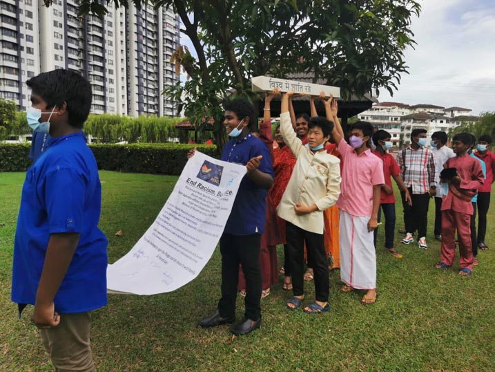 youth in Malaysia walking while holding a sign End Racism