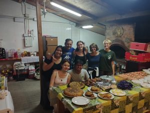 Group photo of people, it seems they are in a kitchen and were helping and preparing food